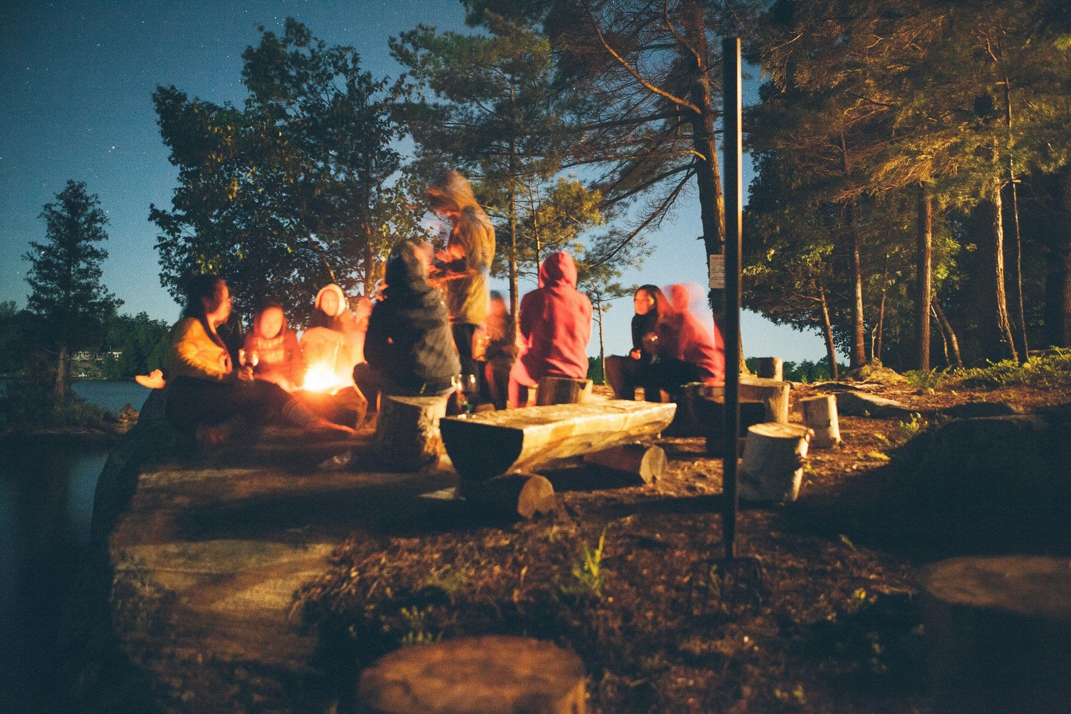 Young people gathered around a fire at dusk forming relationships
